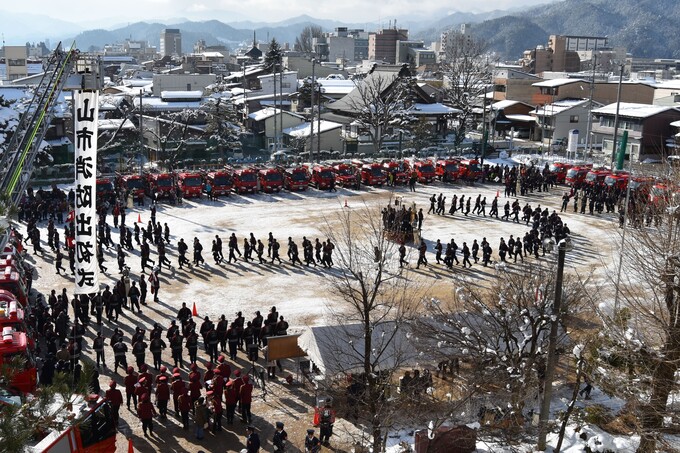 平成29年に開催された市政施行80周年記念の出初式の画像。消防団員が隊列を組んで渦巻き状の隊形をとる訓練。