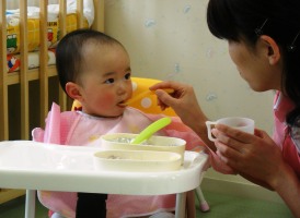 病児保育室で保育師からご飯をもらう幼児の写真