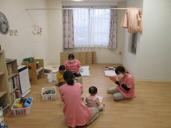 病児保育室で保育士からご飯をもらう幼児の写真