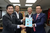 青谷正史さんと市長が児童書「守山昔ばなし」をもっている写真