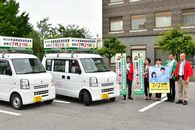 啓発車両と並んでポスターとのぼり旗をもって選挙啓発をする市職員