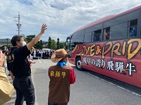 写真：手を振りながら出品者の乗るバスを見送る田中市長