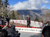 写真：展望デッキから望める槍ケ岳、穂高連峰を指し示しながら挨拶をする田中市長