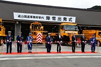 写真：除雪車を前にテープカットをするようす