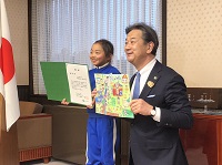 写真：「平和なまち」が描かれた作品と賞状とともに市長と記念撮影をする矢箆原さん