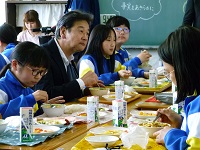 写真：児童らと向い合せの席でソフト麺カレーを食べる田中市長