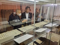 写真：堀祥岳 歴史まちづくりネットワーク委員長から展示資料の説明を受ける田中市長