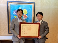 写真：田中市長から紺綬褒章の伝達を受ける伏見社長