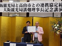 写真：締結した連携協定書を手にする溝端理事長と田中市長