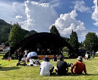 写真：清見町ウッドフォーラム飛騨の野外ステージでのライブを芝生の上で楽しむ観客