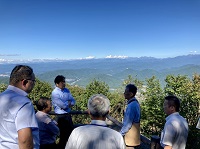 写真：青く澄む空と眼下に広がる久々野の町並みを望みながら船山の眺望などの説明を聞くようす