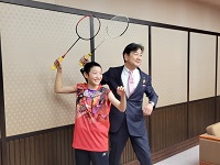 写真：バドミントンラケットを手に笑顔で構えのポーズをとる上野さんと田中市長