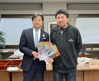 写真：5月25日飛騨の里で開催されるジャズフェスティバルのチラシを市長に手渡す久田さん