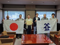 受贈した国旗と市旗を手に快晴会の方々と記念撮影