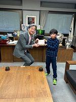小学3年生の亀井さんから手書きの提案書を受け取る市長