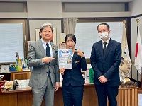 Hotel and Spa Gift TAKAYAMAの副支配人らとこども食堂のチラシを手に市長と記念撮影